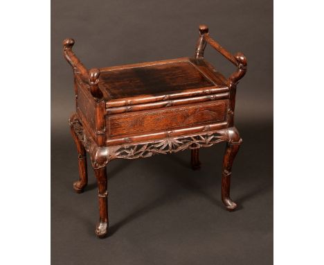 A Chinese padouk wood piano stool, hinged cover flanked by scroll supports, above a deep frieze and shaped apron carved and p