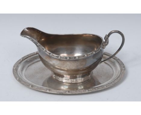 An Arts and Crafts style silver sauce boat and stand, each applied with a border of cabochons and knotted motifs in the Celti