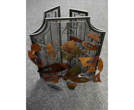 A metal three-way folding fire screen together with a piece of metal wall art 