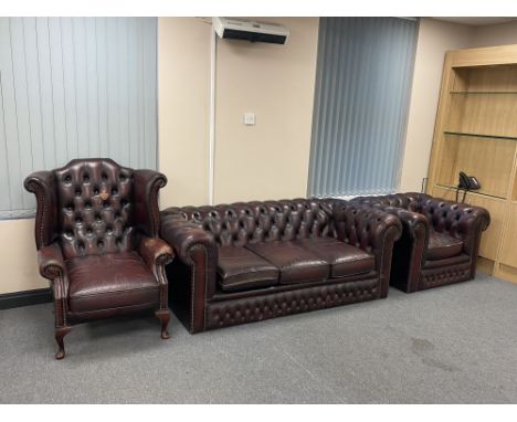 A three piece Chesterfield style oxblood button leather suite; wingback chair, three seater club settee and club armchair 
