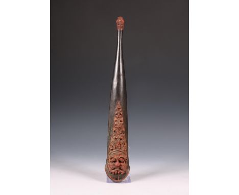 Bali, a carved wooden lance sheath, ca. 1900; with in high relief two carved demon faces and flames. In red and black. L. 42 