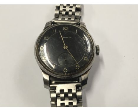 A Gents Longines Watch circa 1940, with a black dial. Manual wind in working order with a later steel bracelet. Postage to th