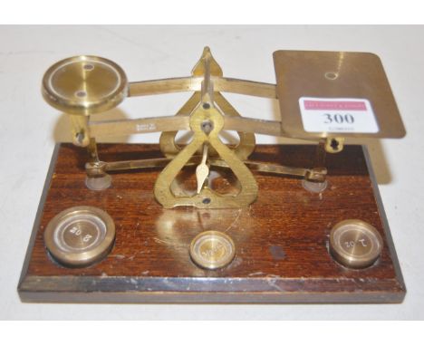 A pair of brass postal scales and weights on wooden plinth