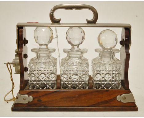 An early 20th century oak and silver plated miniature three bottle tantalus with key