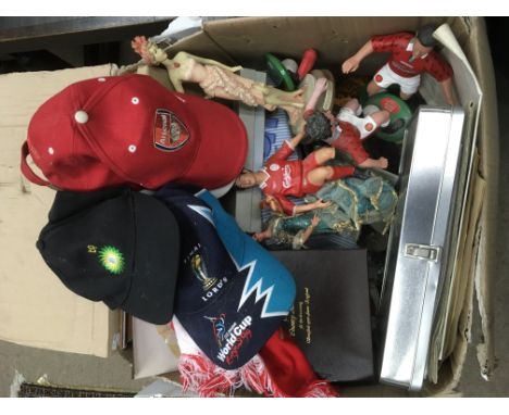 A box of oddments comprising ceramic figures, pictures, baseball caps and other items.