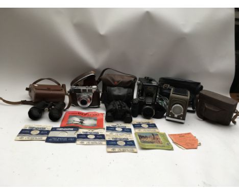 A box containing a collection of cameras and binoculars, as well as Viewmaster one reel slides. Includes Kodak, Ilford camera