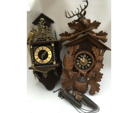 Two wall mount clocks, including a carved wood Cuckoo clock with weights. Both having Roman numerals to the dials