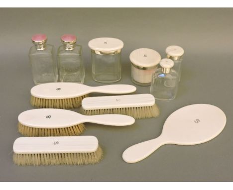 A dressing table set, including four ivory mounted brushes, a looking glass, four bottles with ivory and silver mounts, with 