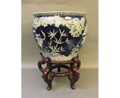 A Chinese ceramic fish bowl, decorated to the interior with koi carp, on hardwood stand