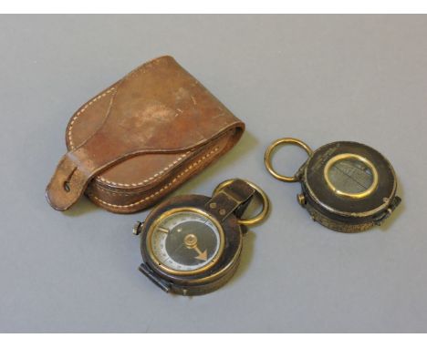 Two brass compasses, one by The Reflector Compass Junior Army and Navy Stores Ltd, the other in a leather case
