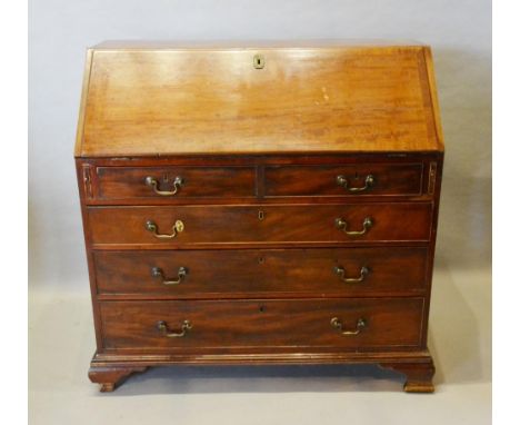 A George III Mahogany Bureau The Fall Front Enclosing a fully fitted interior, above two short and three long drawers with br