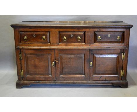 A George III Oak Dresser Base The Moulded Top Above Three moulded drawers and two similar doors with central panel, raised up