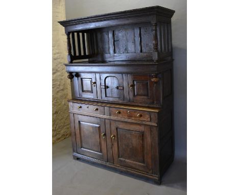 An 18th Century Oak Tridarn The Moulded Cornice above a three panel and slatted back above four moulded cupboards and two dra