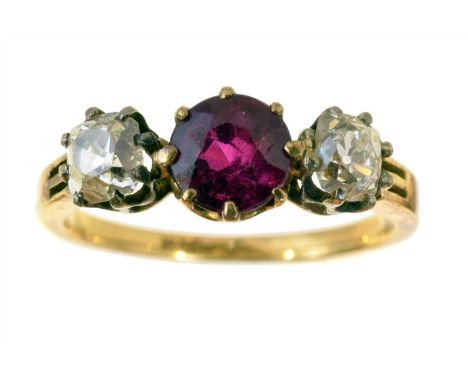 A ruby and diamond three stone ring retailed by Wartski, the circular shape ruby with old cut diamond sides, stamped 18ct, es