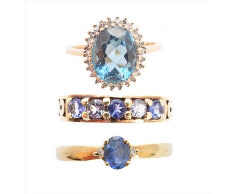 Three 9ct gold gem set rings, to include a blue topaz and diamond cluster ring, a sapphire and diamond three stone ring and o