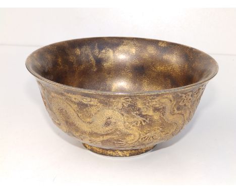 A Chinese porcelain bowl with gold sponged decoration overall, the exterior bearing relief decoration of dragons amidst cloud