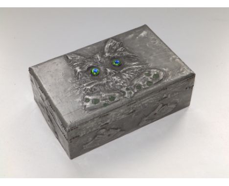 A wooden cigarette box decorated in embossed sheet pewter in the Arts &amp; Crafts style to show the face of a cat in bow tie