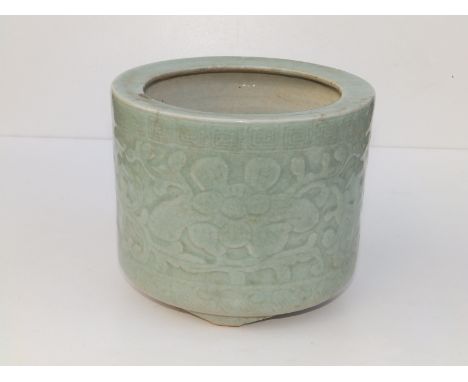 A small antique Chinese celadon glazed jardiniere, of cylindrical form, having incised decoration of a band of Chinese fret a