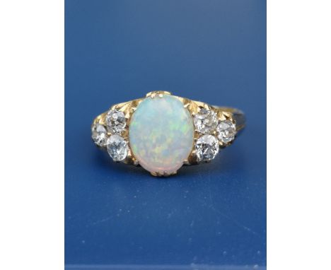 An opal &amp; diamond set 18ct gold ring, the oval claw set opal flanked by six old cut diamonds.  Finger size O.