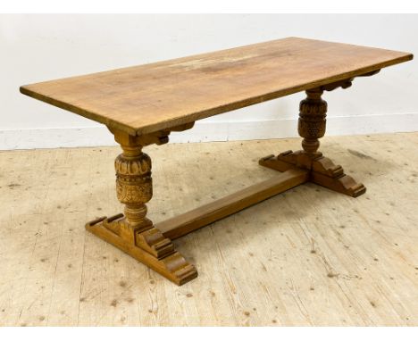 A light oak trencher style kitchen table, raised on carved cup and cover end supports and moulded base (h. 76cm x l.183cm x w