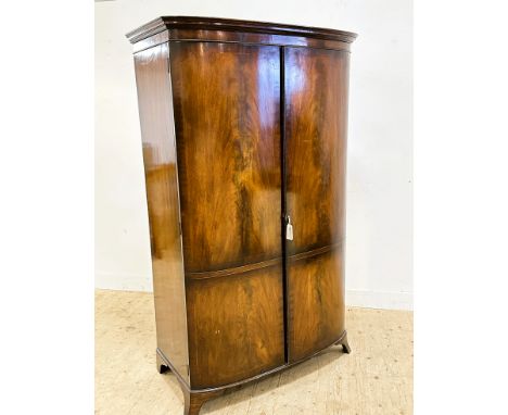 An Edwardian mahogany bow front wardrobe with inlaid panel doors, shelf to top and hanging rail, on splay bracket feet (h.193