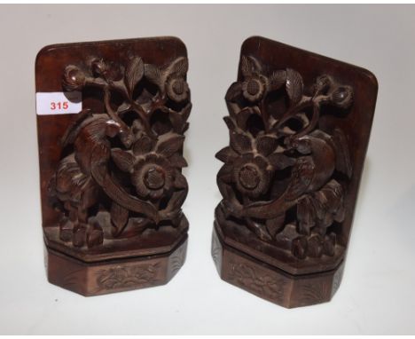 A pair of late 19th Century Oriental hardwood bookends, each carved with an ornamental bird perched on a tree trunk with flow