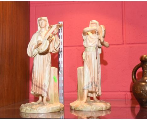 A pair of James Hadley Worcester porcelain figures of Eastern Musicians, in blush ivory, one holding a tambourine, the other 