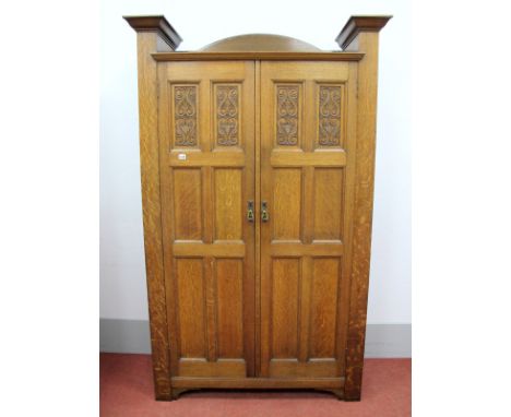 An Early XX Century Johnson and Appleyards Ltd Oak Wardrobe, the top with half round back, the twin doors each with four carv