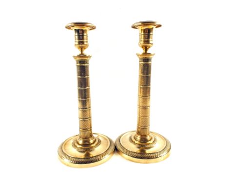 A pair of early 19th Century French Brass candlesticks with detachable sconces and engine milled decoration to the cylindrica
