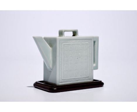 A square Chinese celadon glazed teapot with relief design, Qianlong mark, 19/20th C.  L.: 14,5 cm - H.: 11 cm (incl. stand)  