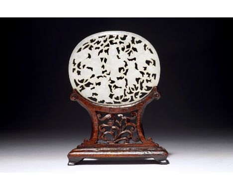 A Chinese reticulated jade plaque, on wooden stand, 19th C.  Dim.: 7 x 6 cm (the plaque)H.: 10,5 cm (on stand)  Condition rep