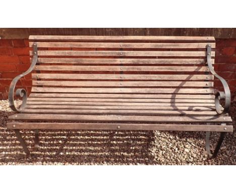 A garden bench with slatted wooden seat and scrolled cast iron ends, 153cm wide 