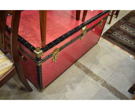 A large travel trunk having brass clasp and corners, currently locked but appears to be empty
