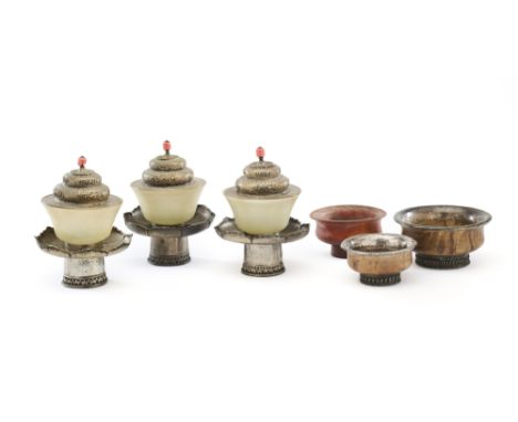 A GROUP OF TEA BOWLS, TIBET, CIRCA 1900 ◉ comprising three jade bowls with engraved brass lotiform stands and domed lids, the