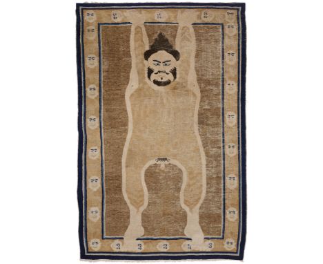 A NINGHSIA TANTRIC RUG, NORTHWEST CHINA, MID 19TH CENTURY the figure against a soft donkey brown ground, his hands and feet b