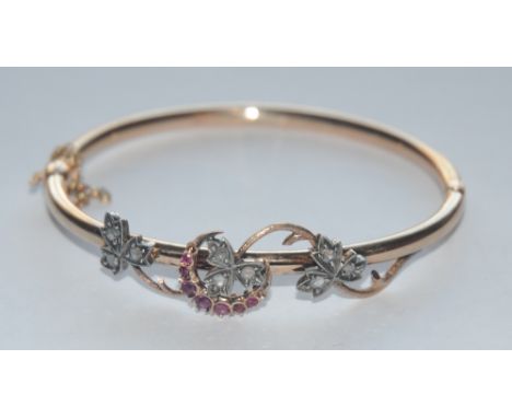 A diamond and ruby floral crescent hinge bangle, inset with nine rose cut diamonds and seven pinky red graduated rubies, holl