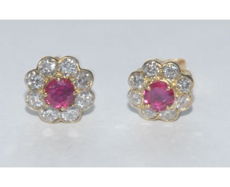 A pair of ruby and diamond floral cluster earrings, each with a central red ruby surrounded by a band of eight round brillian