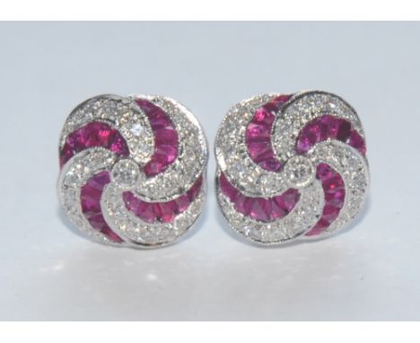 A pair of diamond and ruby quarter lobed vortex cluster earrings, each pave encrusted with brilliant  and free form cut  rubi