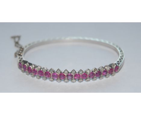 A ruby and diamond hinge bangle, inset with sixteen pinky red certified Burmese's and Thai rubies, each divided by a pair of 