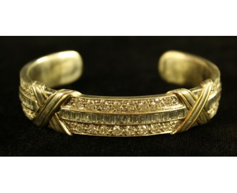A diamond double X cuff bangle, arched open yellow and white two tone body inset with a central row of forty one baguette and