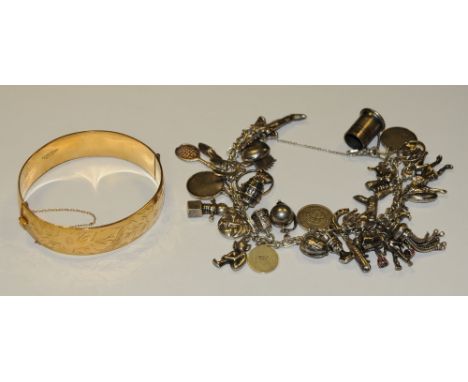A silver charm bracelet;  a gold plated hinged bangle (2)