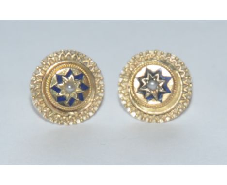A pair of black enamel and seed pearl circular shield boss earrings, single central seed pearl within black star collar, step
