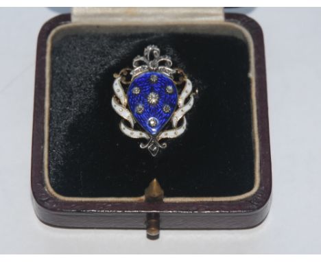 A diamond and enamel shield brooch, the shield-shaped panel highlighted with seven individual lasque-cut diamonds to a blue e