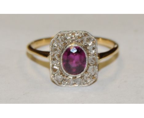 An Art Deco diamond and ruby cluster ring, central oval vibrant purply red ruby approx 0.60ct, surrounded by a collar of four