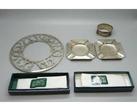 Two silver ashtrays, a silver napkin ring, a silver mounted glass stand and two sealed and boxed silver spoons, (ashtrays and