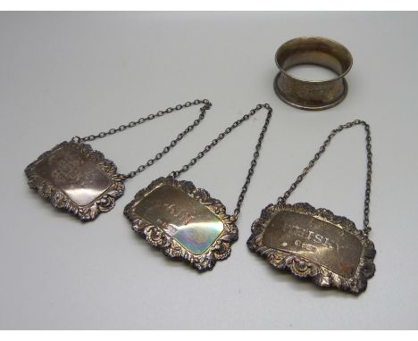 A set of three silver spirit labels and a silver napkin ring, 53g 