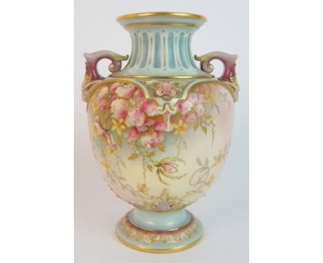 A Royal Worcester blush ware vase with moulded lions head finial handles, the body decorated with flowers and raised gilding 