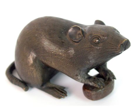 A Japanese bronze model of a rat seated holding a large nut, signed on the base, 9cm long