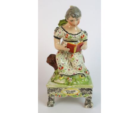 A 19th Century Staffordshire pottery figure "Village Maid" the female seated on a tree trunk reading, raised on a square plat