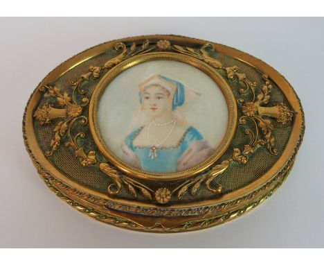 An early 20th Century portrait panel trinket box the oval gilded metal box decorated with raised applied scrolls, leaves and 